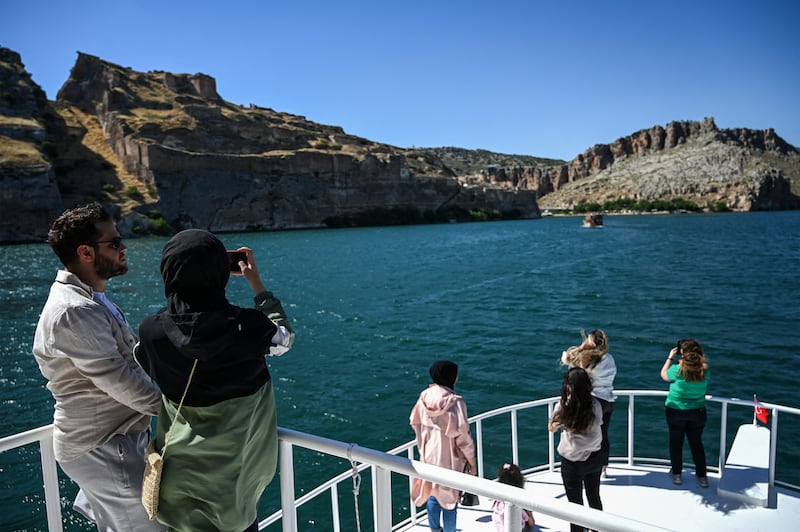 People enjoy a boat tour on a lake in Halfeti, home to the black rose.  