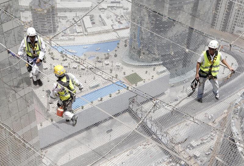 Rope access experts from MEGARME walk across a net 800ft above the ground as they construct the penthouses. Antonie Robertson / The National