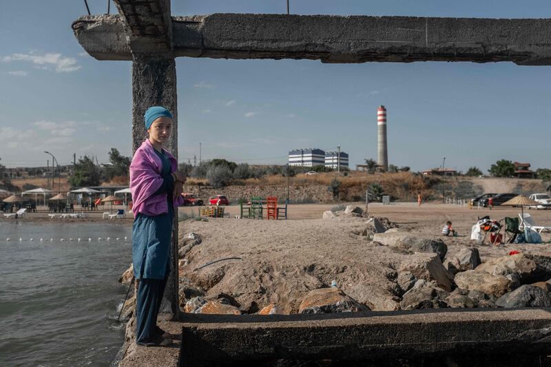 A young woman stands on the water edge along the beach close to the coal-fired Karabiga Cenal power station in Canakkale Province