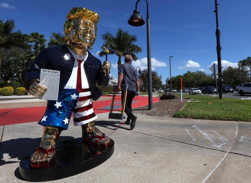 Artist Tommy Zegan walks away from his golden Donald Trump statue after moving it across the street from the hotel that hosted CPAC in Orlando. AP