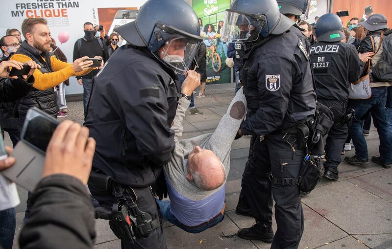 Policemen carry away a participant of the demonstration on Alexanderplatz in Berlin. AP Photo