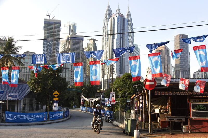 A motorcyclists rides past campaign flags and banners as the Petronas Twin Towers stand in the background in Kuala Lumpur, Malaysia, on Tuesday, May 8, 2018. Malaysia is holding a general election on May 9. Photographer: Ore Huiying/Bloomberg