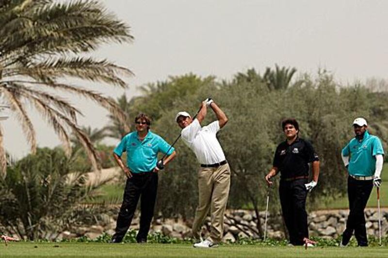 Coach Chris Vallender, left, watches Ahmed Al Musharrekh tee off at the Abu Dhabi Golf Club, with UAE team members Khalid Yousuf (in black) and Abdullah Al Musharrekh.