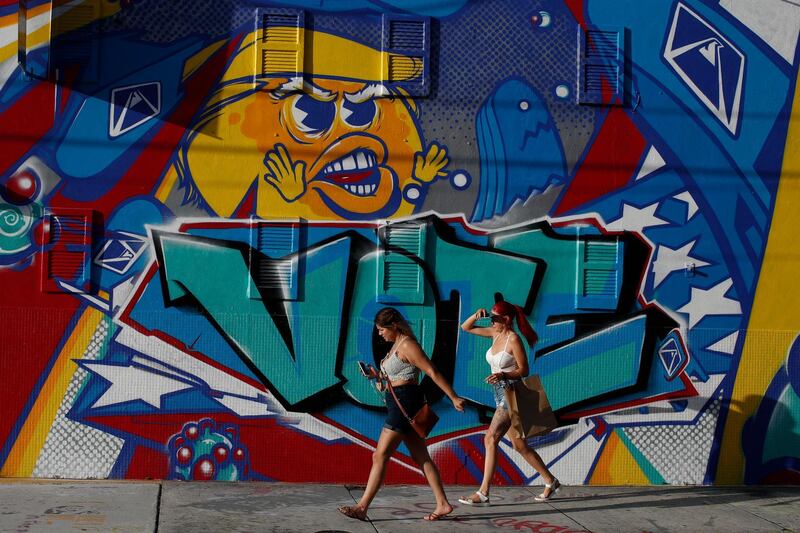 People walk past an election-themed mural by artist Mr Ewok One, outside the Museum of Graffiti in Miami, Florida. AP Photo