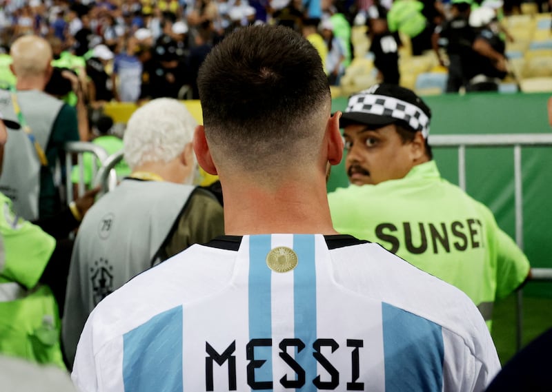 A security guard turns to look at Lionel Messi as the clashes continue in the stands. Reuters