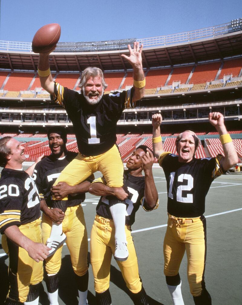 CROCKETT - APRIL 12: Kenny Rogers suits up with the Pittsburgh Steelers, for the singers third CBS television special, "Kenny Rogers America." (also known as Kenny Rogers: Working America.)  Originally broadcast Thursday, November 20, 1980. Steelers football players with Kenny. Left to right: Rocky Bleier (20); Mean Joe Greene (75); Kenny Rogers (1); Lynn Swann (88); and Terry Bradshaw (12). (Photo by CBS via Getty Images) 