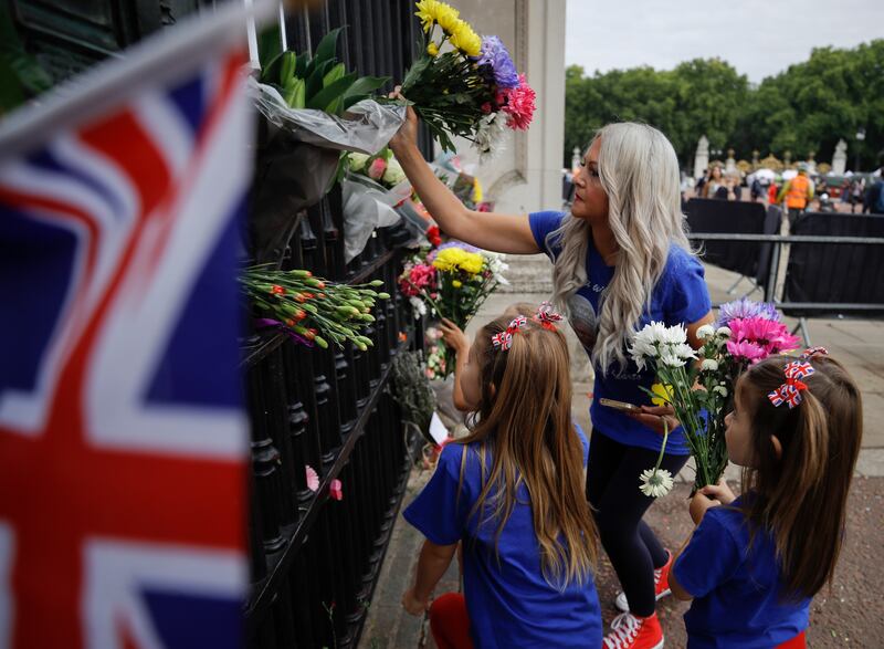 A family leaves flowers outside Buckingham Palace. EPA