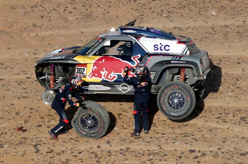 X-Raid Mini JCW Team's Stephane Peterhansel and co-driver Edouard Boulanger attend to their car. Reuters