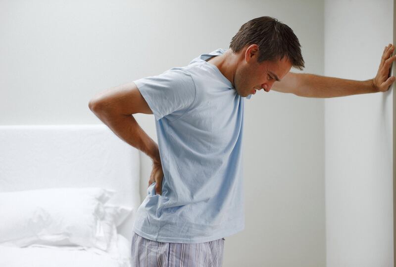 Man with backache leaning against wall