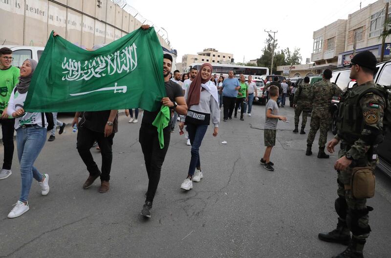 Palestinian security forces stand guard as local football fans carry the Saudi flag ahead of today's match between their national football team and that of Saudi Arabia for a WC2020 qualifying match, in the Israeli occupied West Bank town of al-Ram. On the left is a section of the Israel's controversial seperation barrier.  The game would mark a change in policy for Saudi Arabia, which has previously played matches against Palestine in third countries. Arab clubs and national teams have historically refused to play in the West Bank, where the Palestinian national team plays, as it required them to apply for Israeli entry permits. AFP