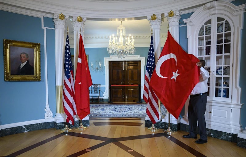 A State Department staffer adjusts a Turkish flag before a meeting between US Secretary of State Mike Pompeo and Turkish Foreign Minister Mevlut Cavusoglu  at the US Department of State in Washington, DC on April 3, 2019.  / AFP / ANDREW CABALLERO-REYNOLDS
