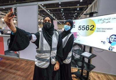 Abu Dhabi, United Arab Emirates, August 6, 2020. 
 Volunteers take a selfie in front of the monitor at the ADNEC volunteer facility showing that the five thousand total vaccination record has been broken.
Victor Besa /The National
Section: NA
Reporter:  Shireena Al Nowais