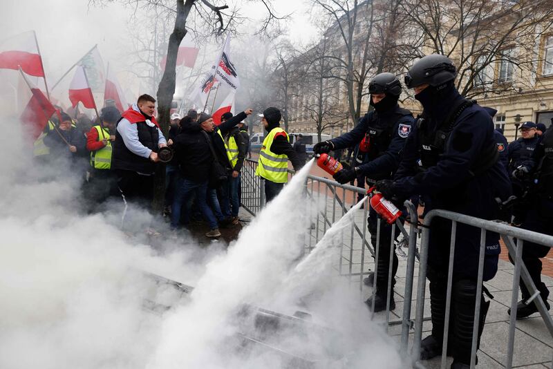 Police put out a fire during a protest by Polish farmers demonstrating against EU climate measures and Ukrainian imports, in Warsaw. AFP