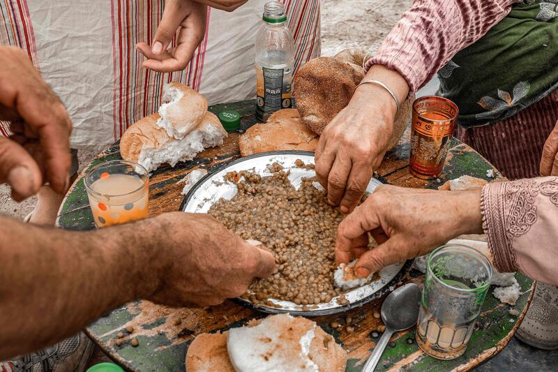 Residents share a meal of lentils in their tent. AFP