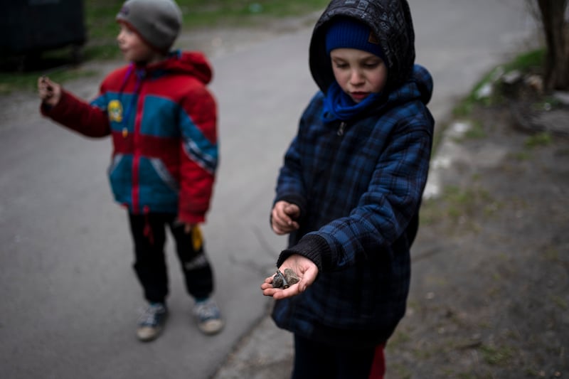 A boy shows the shell of a bullet in Bucha. AP
