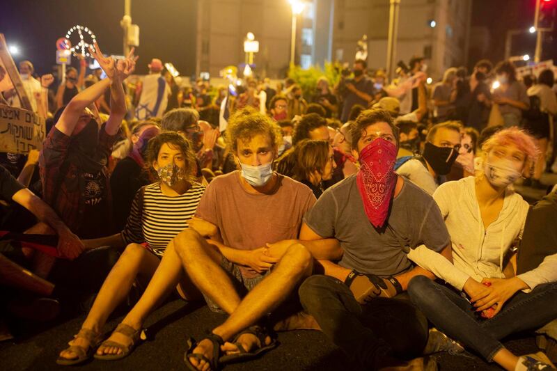 Protesters link arms as police move in to clear the square outside of Prime Minister Benjamin Netanyahu's residence in Jerusalem, late Saturday, Aug. 22, 2020. (AP Photo/Maya Alleruzzo)