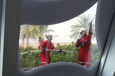  Cleaners wipe the glass windows at the Dubai Frame during humid and hazy conditions in Dubai. Pawan Singh / The National