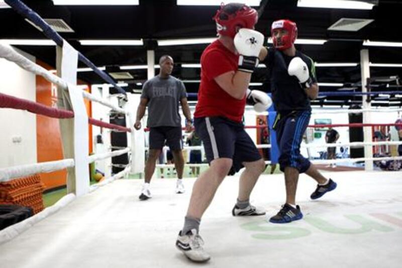 The boxing coach Ricky Miller, back, watches Jaafar Al Aidaroos, front, and Adam Buck preparing for the big Friday fight, the grand finale of the Corporate Contender white-collar boxing programme. Fatima Al Fatima Al Marzooqi / The National