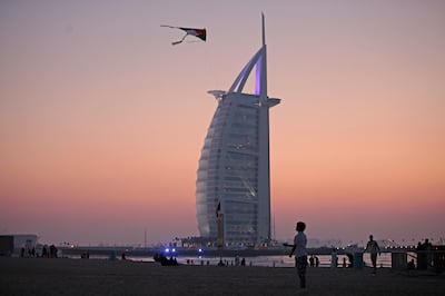 DUBAI, UAE. December 2, 2013 - A boy flies a UAE flag kite with the Burj Al Arab in the background by Umm Suqiem Beach  in Dubai, December 2, 2013.  (Photo by: Sarah Dea/The National, Story by: Martin Croucher, News)


 *** Local Caption ***  SDEA021213-nationaldayPM01.JPG