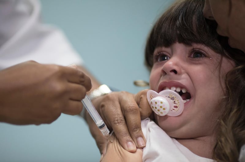 FILE - In this file photo dated Monday, Aug. 6, 2018, a child receives a measles vaccination in Rio de Janeiro, Brazil.  The World Health Organization (WTO) said Monday Aug. 20, 2018, the number of measles cases in Europe jumped sharply during the first six months of 2018 with at least 37 people dead from the disease, and called for increased immunization rates to prevent an endemic.  (AP Photo/Leo Correa, FILE)