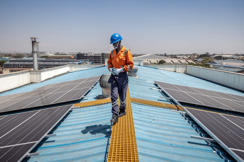 A technician walks on a roof at a partially solar-powered factory in Nairobi. AFP