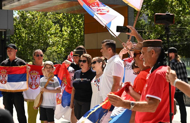 Supporters of Novak Djokovic hold national flags as they gather in front of Federal Court building . AFP