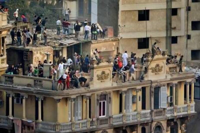 Pro-government demonstrators take to the rooftops to throw rocks down at anti-government demonstrators below, unseen, opposite the Egyptian Museum in Tahrir square in Cairo, Egypt Wednesday, Feb. 2, 2011. Ben Curtis / AP Photo