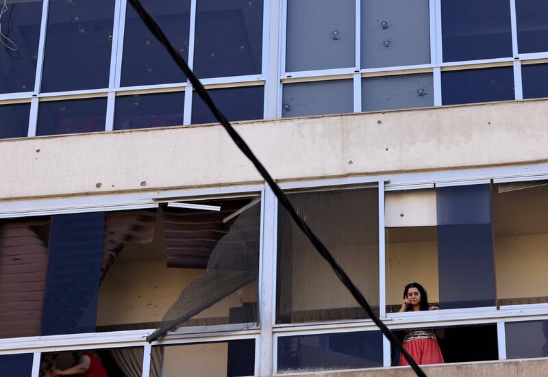 A woman talks on the phone as she stands on her damaged balcony in the district of Ain Al Remaneh, where some of the worst clashes took place. AFP