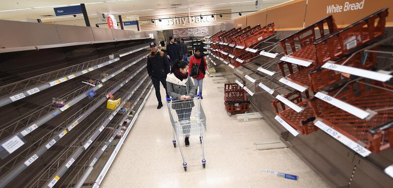 Shoppers look over empty shelves at a Tesco supermarket in London. EPA