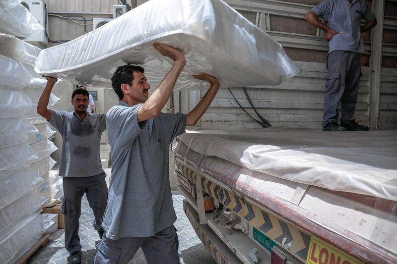 Workers haul mattresses across the factory. Victor Besa for The National