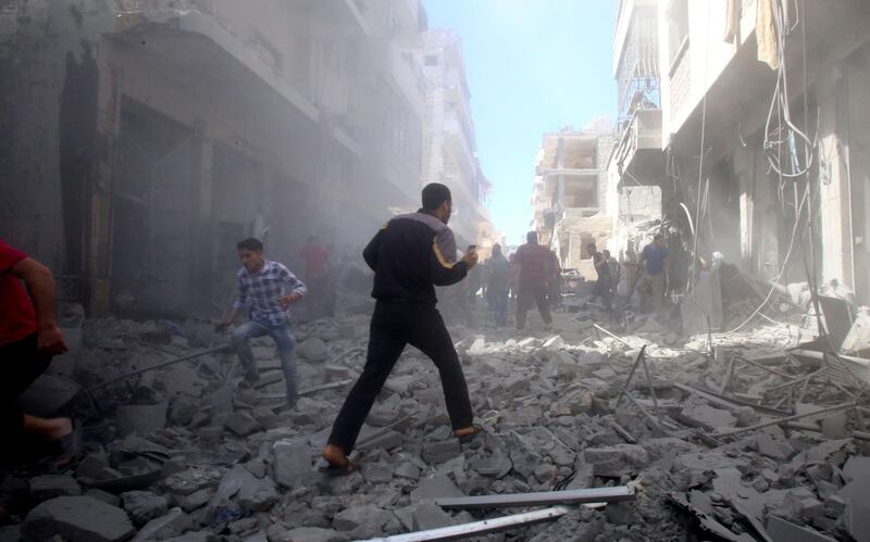 People walk among debris following a reported air strike by regime forces and their allies in the jihadist-held Syrian town of Maaret Al-Noman in the southern Idlib province, on May 26, 2019.  / AFP / Abd el-Aziz Qitaz
