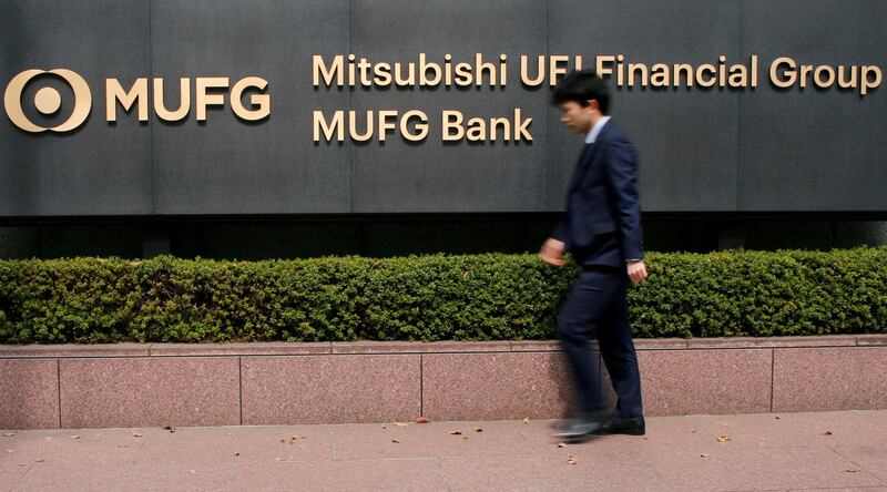 FILE PHOTO: A man walks past a signboard of Mitsubishi UFJ Financial Group and MUFG Bank at its headquarters in Tokyo, Japan April 3, 2018. REUTERS/Toru Hanai/File Photo