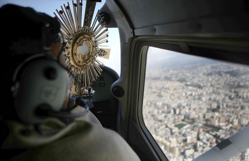 Maronite priest Majdi Allawi holds the Blessed Sacrament as he blesses Lebanon from an aircraft as protection from disease. AFP