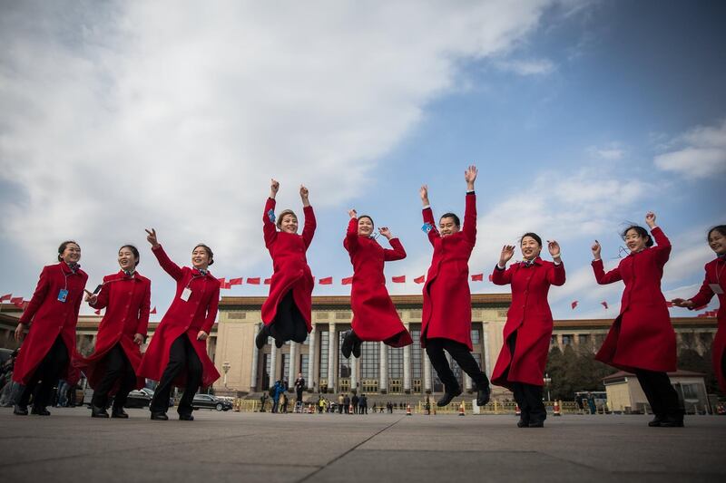 Hospitality staff members jump as they pose for photos in front of the Great Hall of the People during the closing of the First Session of the 13th Chinese People's Political Consultative Conference National Committee at the Great Hall of the People (GHOP) in Beijing, China. Roman Pilipey / EPA