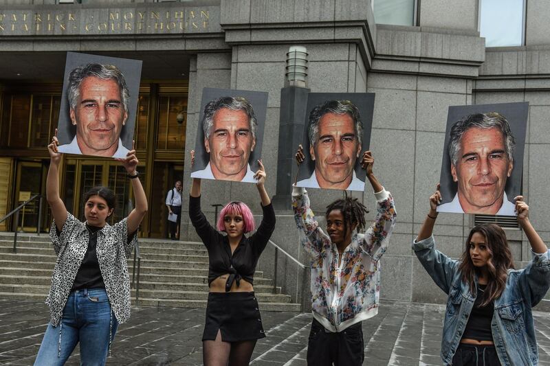 (FILES) In this file photo taken on July 8, 2019, a protest group called "Hot Mess" hold up photos of Jeffrey Epstein in front of the Federal courthouse on July 8, 2019 in New York City.  The wealthy US financier Jeffrey Epstein, indicted on charges he trafficked underage girls for sex, committed suicide in prison, US news media reported on August 10, 2019. Epstein, who had hobnobbed with politicians and celebrities over the years and was already a convicted sex offender, hanged himself in his cell at the Metropolitan Correctional Center and his body was found around 7:30 Saturday morning, The New York Times and other media said, quoting officials.  / AFP / GETTY IMAGES NORTH AMERICA / STEPHANIE KEITH
