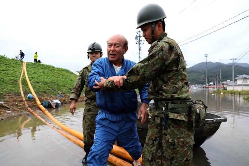Japanese troops guide a man from a flooded area during search and rescue operations in the aftermath of Typhoon Hagibis in Marumori, Miyagi prefecture. AFP