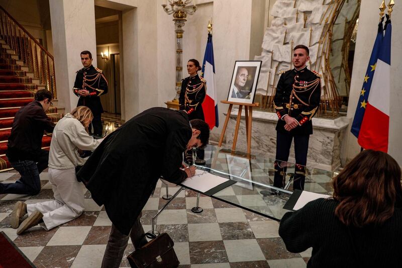 People sign condolence registers for late former French President Jacques Chirac at the Elysee presidential palace in Paris on September 26, 2019 after the announcement of his death today at the age of 86 after a long battle with ill-health, his family said. / AFP / GEOFFROY VAN DER HASSELT
