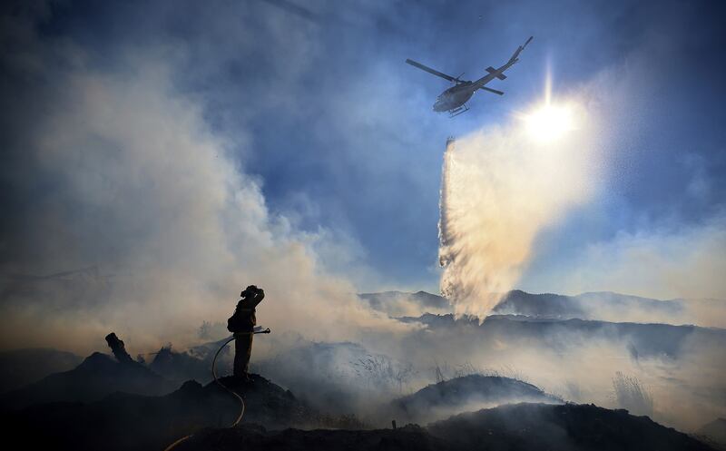 Brian Klatt, a Ukiah Valley Fire Authority firefighter in California, pauses as a helicopter makes a drop on a fire.