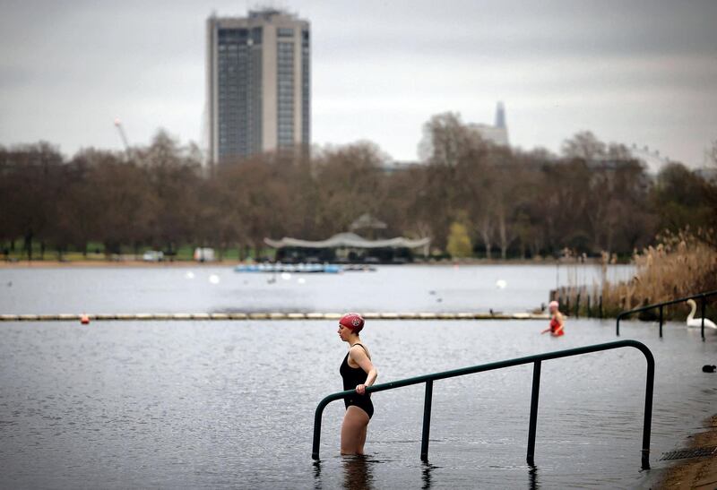 A bather enters the water to swim in the Serpentine Lido in Hyde Park, London as England's third Covid-19 lockdown restrictions ease, allowing outdoor sports facilities to open on March 29, 2021. England began to further ease its coronavirus lockdown on Monday, spurred by rapid vaccinations, but governments in the rest of Europe struggled to contain Covid-19 surges. / AFP / Tolga Akmen
