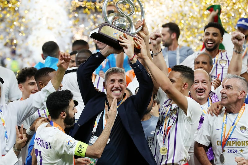 Al Ain manager Hernan Crespo celebrates with the trophy.