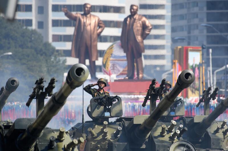 Korean People's Army (KPA) soldiers salute as they ride tanks during a military parade and mass rally on Kim Il Sung square in Pyongyang.  AFP
