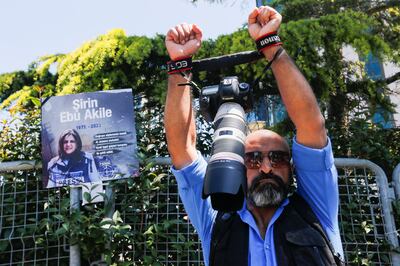 Egyptian journalist Ibrahim El-Masry holds up his camera as he stands next to a placard with a picture of Shireen Abu Akleh, during a protest outside the Israeli consulate in Istanbul. Reuters