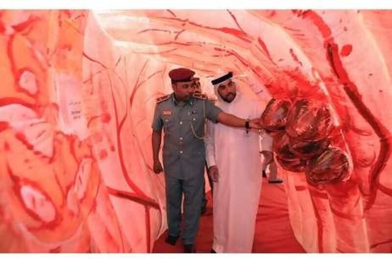 Ayman Kamel Ibrahim, the security officer of Health Authority-Abu Dhabi, right and Sami Zayed al Monzeui, a police officer, walk through a giant replica of a human colon that has been installed at the health authority's headquarters.