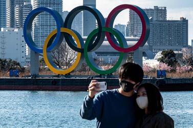 A couple pose for photos in front of the Olympic rings on display at the Odaiba waterfront in Tokyo on February 24, 2021. AFP