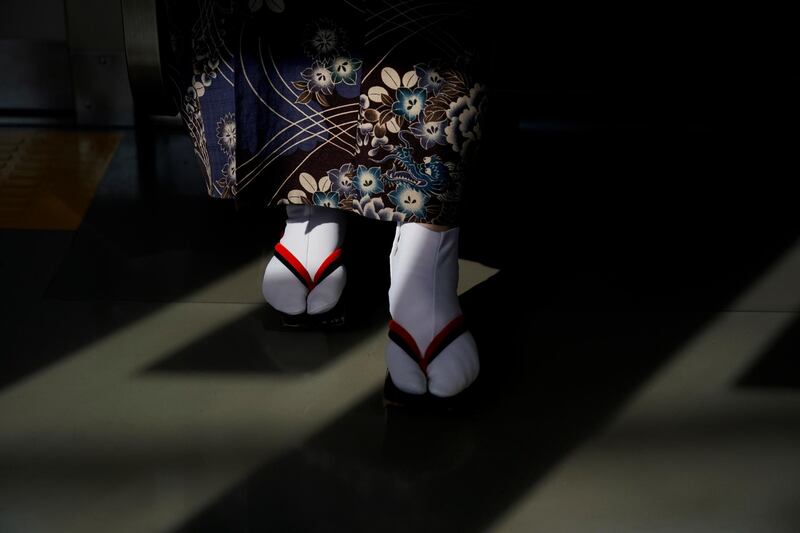 A woman wearing kimono and traditional Japanese sandals is lit by the afternoon sunlight in Kawagoe, near Tokyo. AP Photo