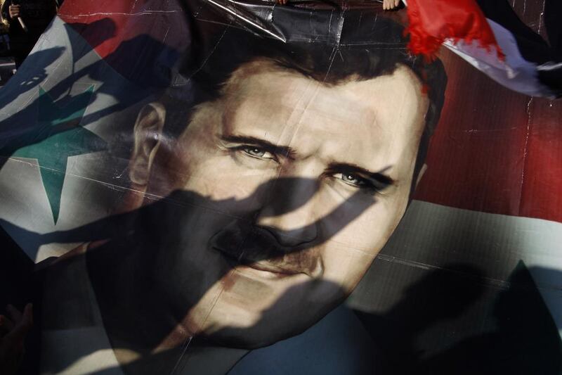 Shadows of Syrians are reflected on a giant poster showing President Bashar Al Assad, during a support rally in Damascus. Muzaffar Salman / AP 