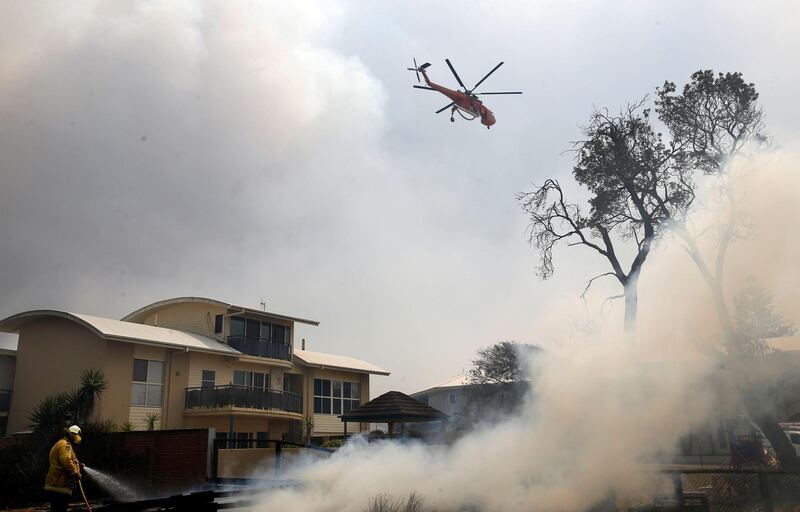 A fire bombing helicopter works to contain a bushfire along Old Bar road in Old Bar, New South Wales, Australia. REUTERS