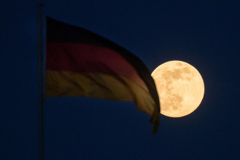 The supermoon illuminates a German national flag flying in Berlin. Bloomberg