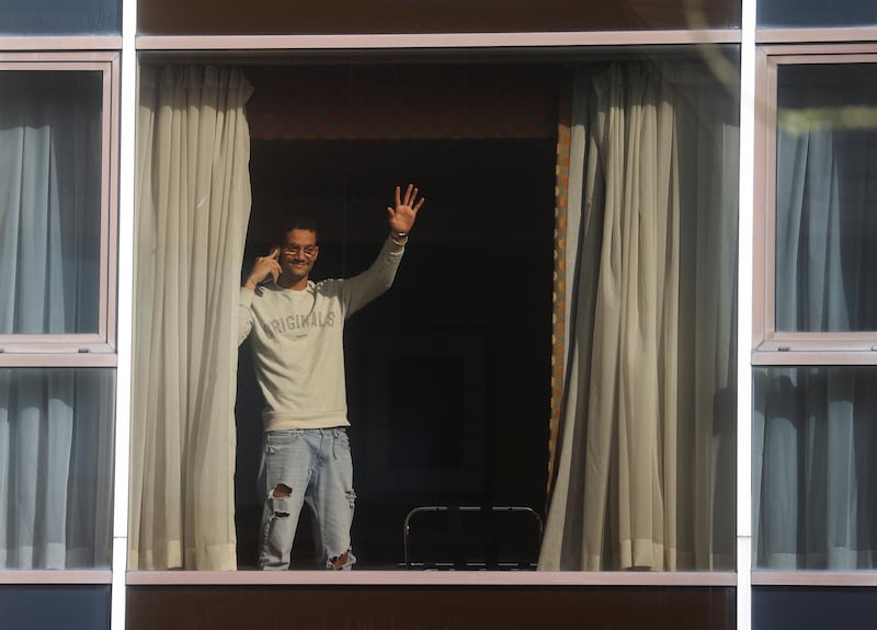 A man waves from the window of the Radisson Blu Hotel at Heathrow Airport, as Britain introduces hotel quarantine programme. Reuters