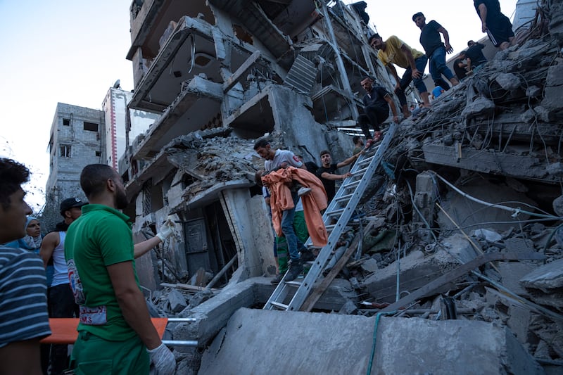 Palestinians rescue a young girl from the rubble of a destroyed residential building following an Israeli air strike. AP